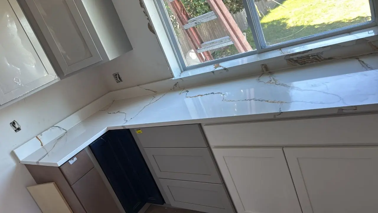Long white stone countertop fitted beneath a kitchen window
